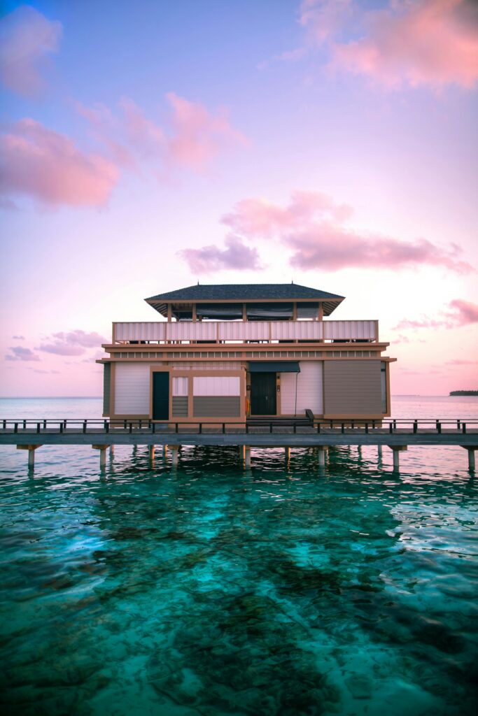 Stunning overwater villa at sunset in the Maldives with vibrant skies and turquoise waters.