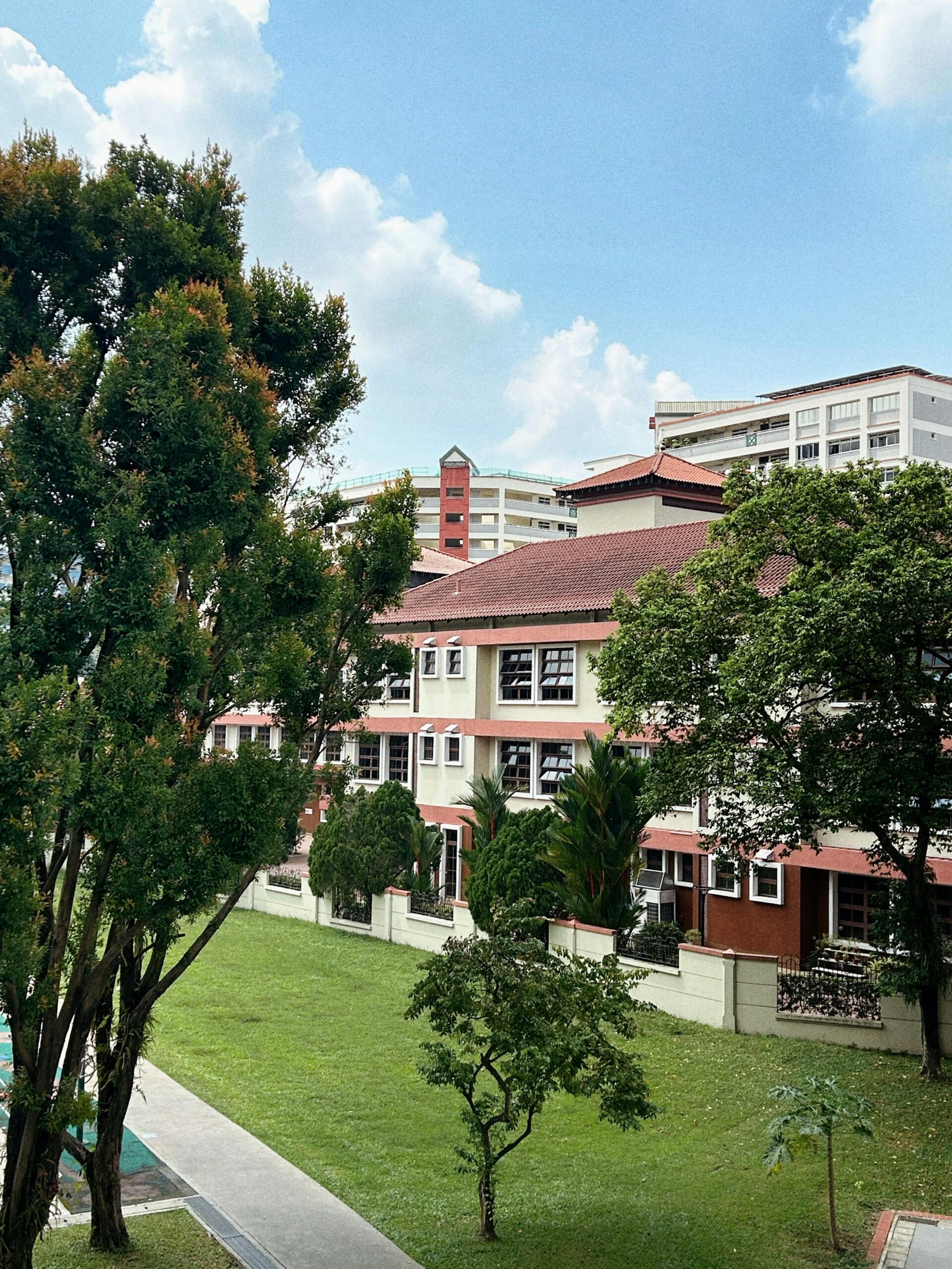 A vibrant urban residential complex surrounded by lush greenery under a bright blue sky.